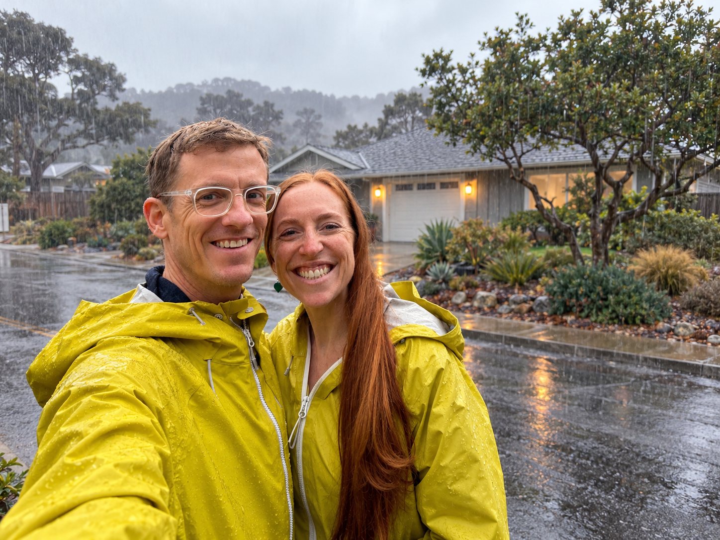 Patrick and Mariah smiling in yellow rain jackets on a rainy Los Osos neighborhood street